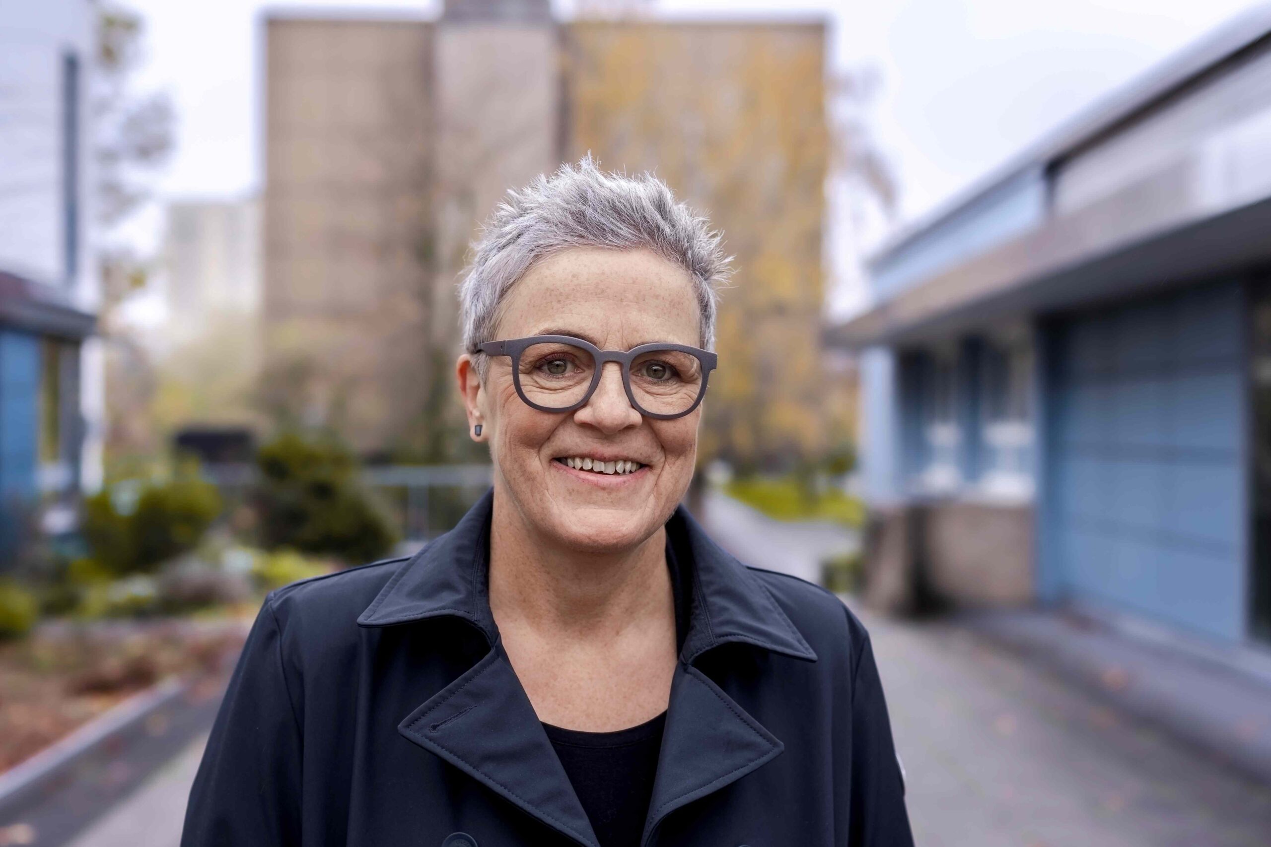 Sylvia Rietenberg steht vor einem Gebäude und lächelt