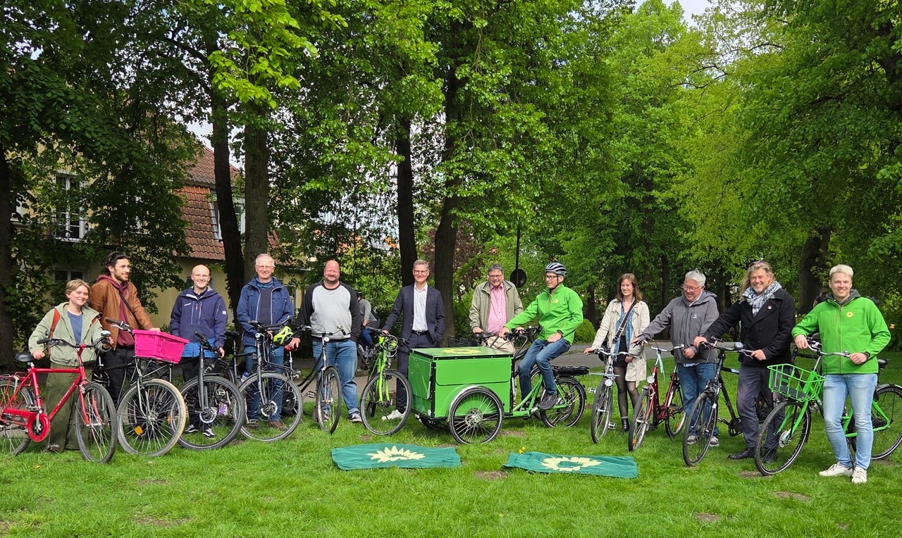 Menschen stehen mit ihren Fahrrädern in einer Reihe für ein Gruppenfoto