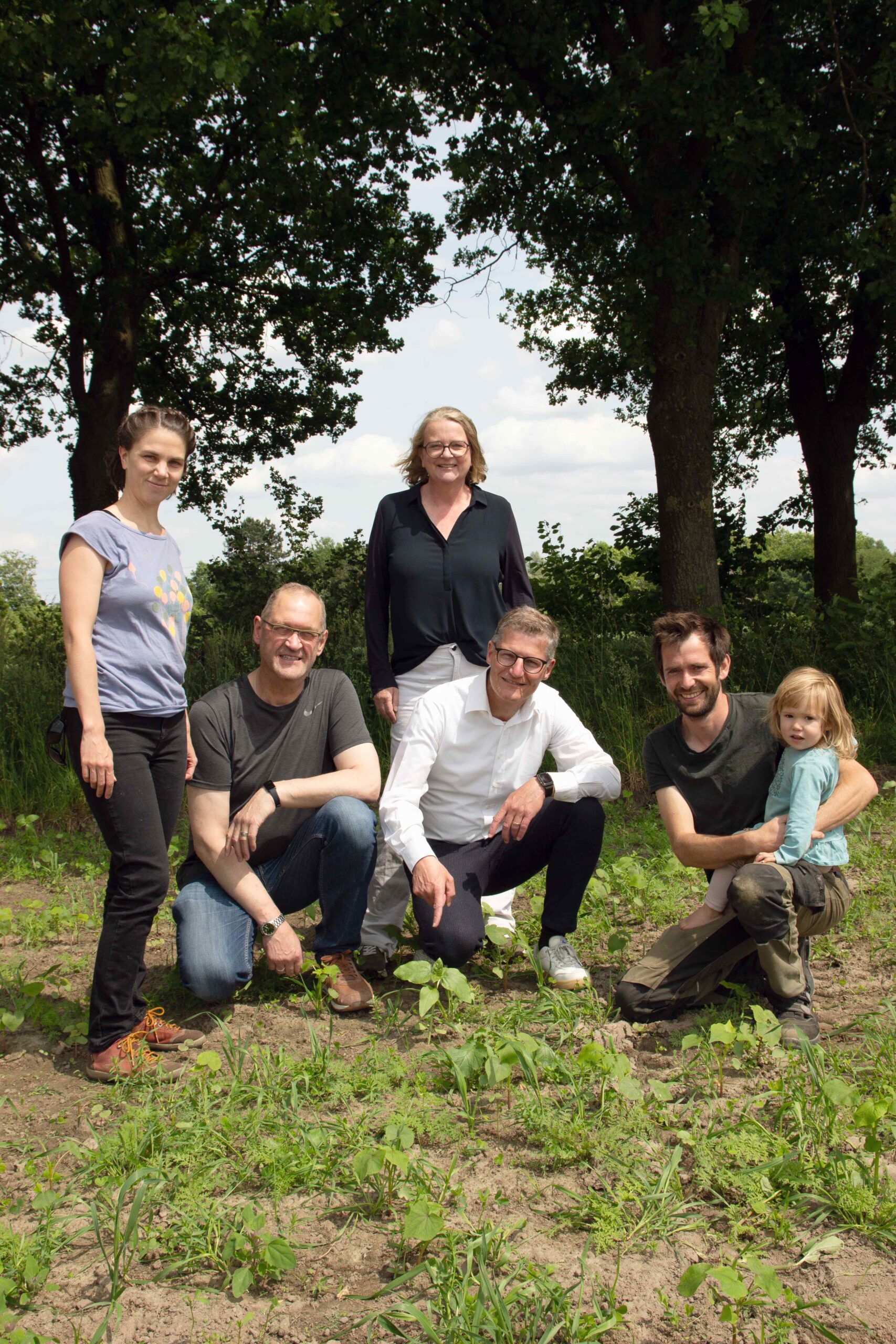 Mehrere Menschen stehen und knien nebeneinander für ein Gruppenfoto